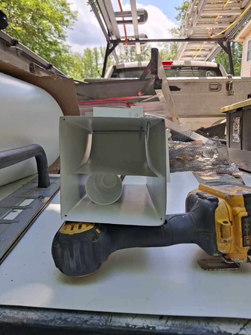 A hand-built sheet-metal one-way door on a truck tailgate, its inner flap visible