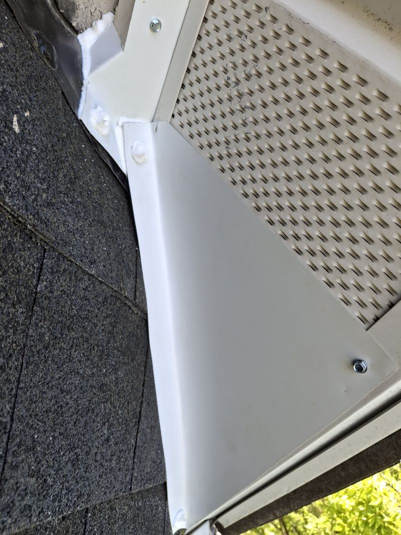A newly fitted white aluminum soffit corner patch sealing a roof gap